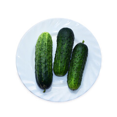 Three cucumbers on a plate isolated top view. Healthy food promotes hydration on a white background. Useful fruit for skin, for weight loss