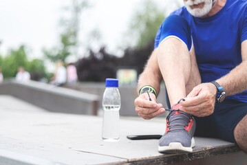 Old sportsman tying shoelace for outdoor exercise
