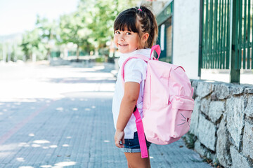 Black-haired girl wearing a pink backpack goes to school. School concept