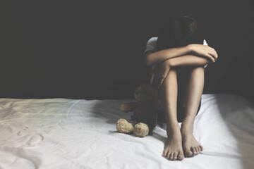 Sad little girl sitting in dark room. human trafficking concept. - obrazy, fototapety, plakaty