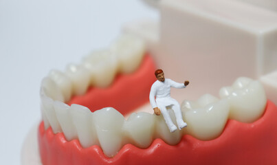 Fototapeta na wymiar A miniature doctor sitting on a tooth model. 