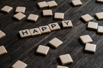 Happy Text. Flat lay photography - Word/s made with lettered tiles on timber background.
