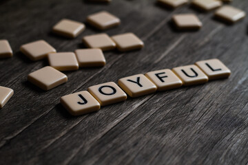 Joyful Text. Flat lay photography - Word/s made with lettered tiles on timber background.
