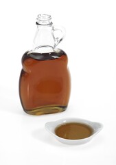 BOTTLE OF MAPLE SYRUP AGAINST WHITE BACKGROUND