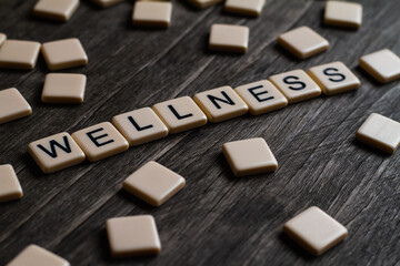 Wellness Text. Flat lay photography - Word/s made with lettered tiles on timber background.