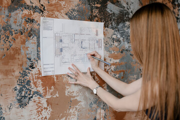 Red haired female enjoying painting plan of building.