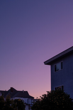 A purple to pink gradient sunset with silhouetted houses