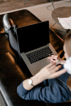 Stylish woman sitting with laptop on knees and using.
