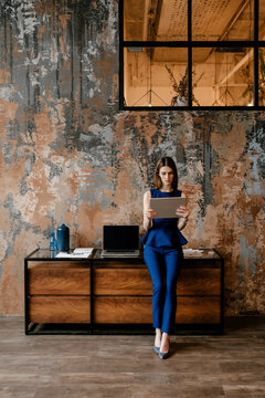 Pretty stylish woman wearing dark blue suite using tablet.