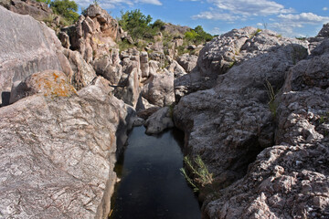 Adventure. Geology. View of the river flowing along the rocky cliffs and stone wall in Mina Clavero, Cordoba, Argentina.