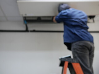 blurred of technician cleaning air conditioner at office.