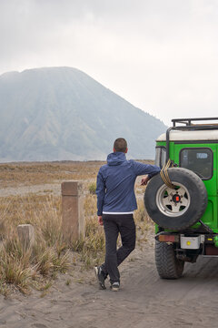 Man visiting Bromo volcano and Leaning To a jeep