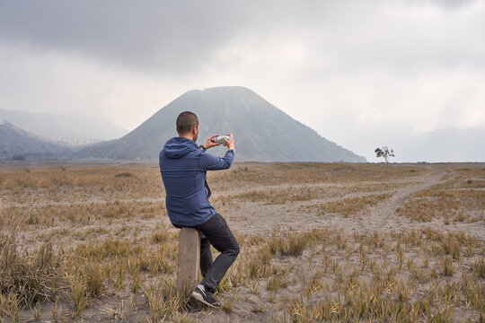 Man visiting Bromo volcano and using a mobile phone to take pictures