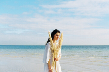Brunette woman with flowers and foliage at the beach
