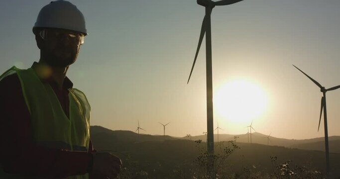 The young engineer examines the windmill and then turns to the camera, throwing his hands on each other
