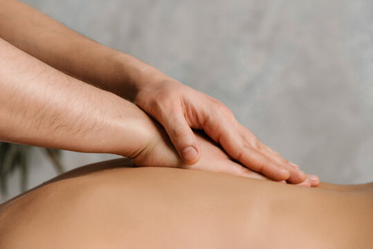 Therapist working with shoulder and warming back by hands.