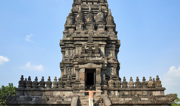 Woman with raising arms standing in front of the gate in Prambanan Temple, Java, Indonesia.