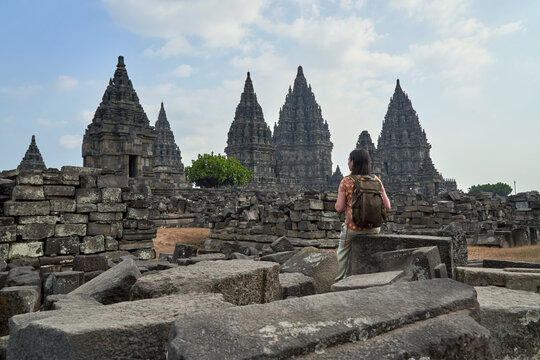 Back view of woman with backpack looking at a stupa in Prambanan Temple, Java, Indonesia