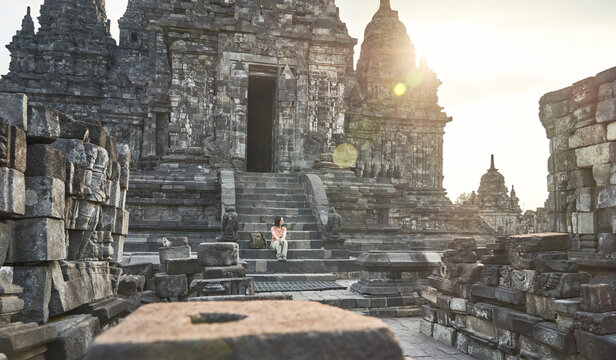 Woman with backpack sitting at the steps of the temple's entrance. in Prambanan Temple, Java, Indonesia