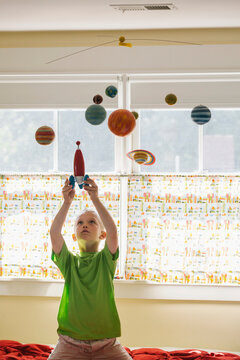 Child Astronaut Blast Off With Toy Rocket Ship And Solar System Mobile