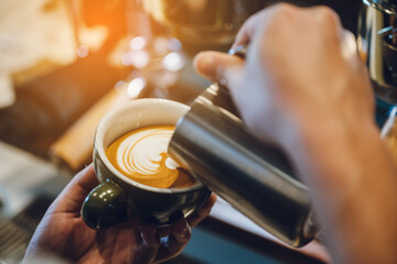 barista making latte art, shot focus in cup of milk and coffee, vintage filter image