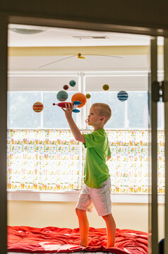 Child Astronaut Imagination with Toy Rocket Ship and Solar System Mobile