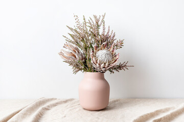 Beautiful floral arrangement including beautiful dried pink King Proteas and delicate thryptomene flowers, in a stylish pink vase.