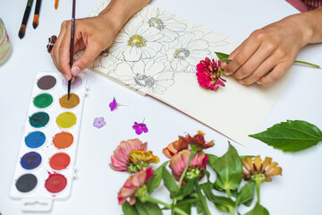 Anonymous female artist painting flowers with watercolors