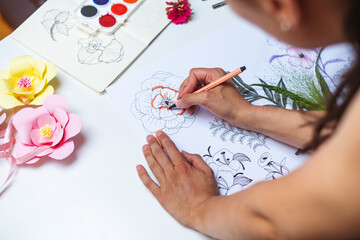 Anonymous female artist drawing flowers on a piece of paper