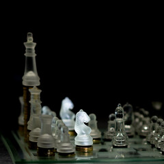 Tablero de ajedrez con piezas transparentes en fondo negro con estrategia defensa de caballos © Carlos Hurtado