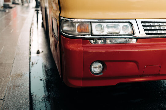 Part of red and yellow bus.Rainy day.