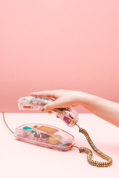 Person Using Transparent Landline Phone On The Pink Background