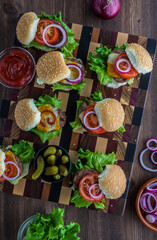 Top down view of beef cheeseburger sliders on a wooden board ready for eating.