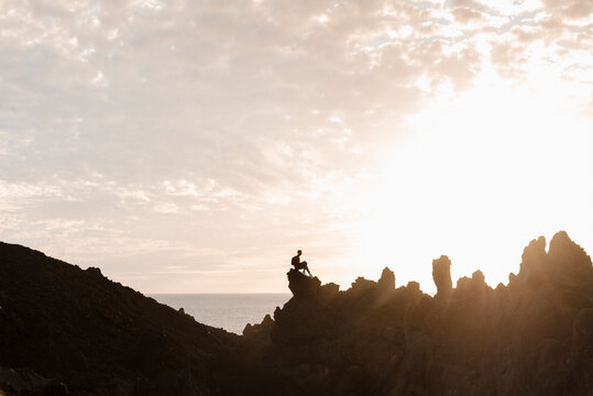 Male sitting relaxing on top of rocky bridge over water. - Powered by Adobe