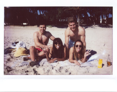 Friends smile and gesture on beach.