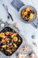 New England clam bake in a roasting pan with a serving of it ready to eat. 