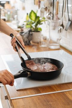 Woman frying delicious steaks turning with tongs