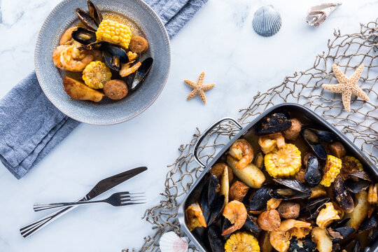 Gourmet traditional New England Clam bake in a roasting pan with a serving of the same ready to eat.