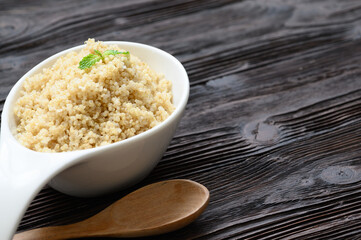 Bowl of boiled quinoa on wood background
