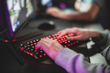Cyber sport e-sports tournament, team of professional gamers, close-up on gamer's hands on a keyboard, pushing button, gamers playing in competitive moba/strategy fps game on a cyber games arena club © tsuguliev