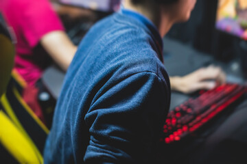 Fototapeta na wymiar Cyber sport e-sports tournament, team of professional gamers, close-up on gamer's hands on a keyboard, pushing button, gamers playing in competitive moba/strategy fps game on a cyber games arena club