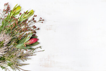 Beautiful flat lay floral arrangement including protea and delicate thryptomene flowers, on a white...