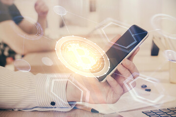 Double exposure of man's hands holding and using a phone and crypto currency blockchain theme drawing.