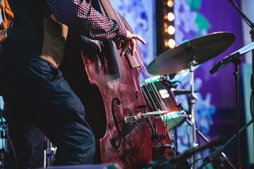 Concert view of a contrabass violoncello player with vocalist and musical during jazz orchestra band performing music, violoncellist cello player on stage - obrazy, fototapety, plakaty