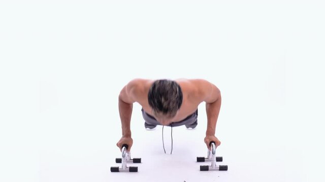 full body image of muscle man without clothes do push up exercises with tools on an isolated background
