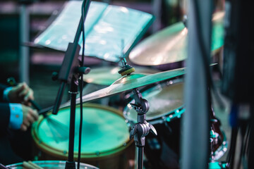 Drummer percussionist performing on a stage with drum set kit during jazz rock show performance, with band performing in the background, drummer point of view
