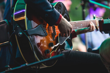 Concert view of an electric acoustic guitar player with vocalist and musical jazz band orchestra...