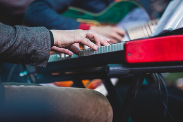 Concert view of a musical keyboard piano player during musical jazz band orchestra performing, keyboardist hands during concert, male pianist on stage, hands close up
