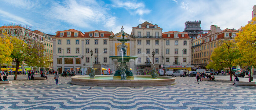 Lisbon, Portugal - May 20, 2019: Rossio Square fountain and colorful historic buildings of historic city center