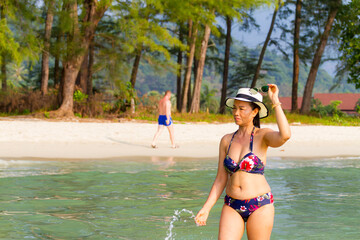 Woman with hat and bikini walk relax at beach